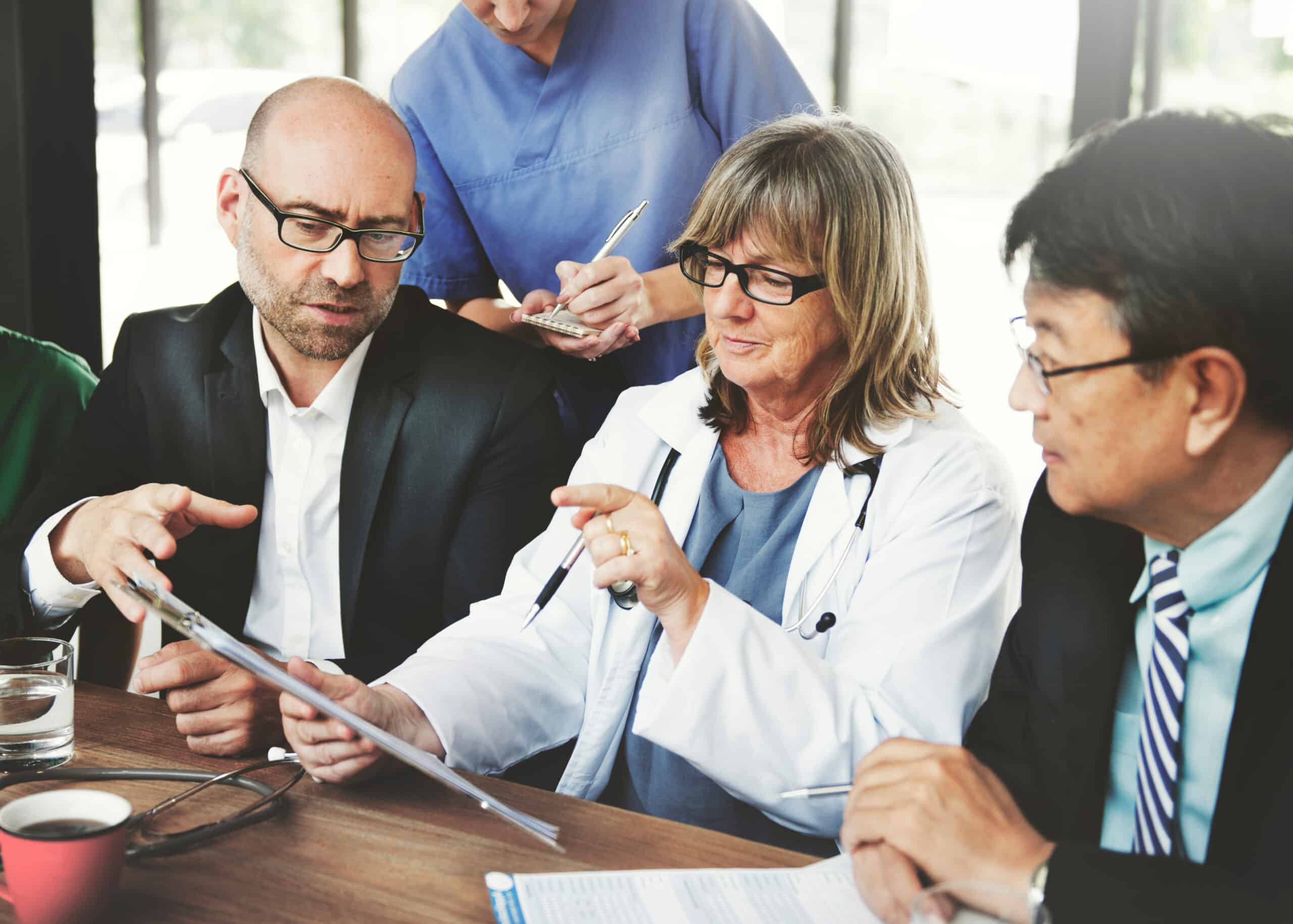 Coworkers, some in scrubs and others in business suits sharing information on complaints and AI in life sciences.